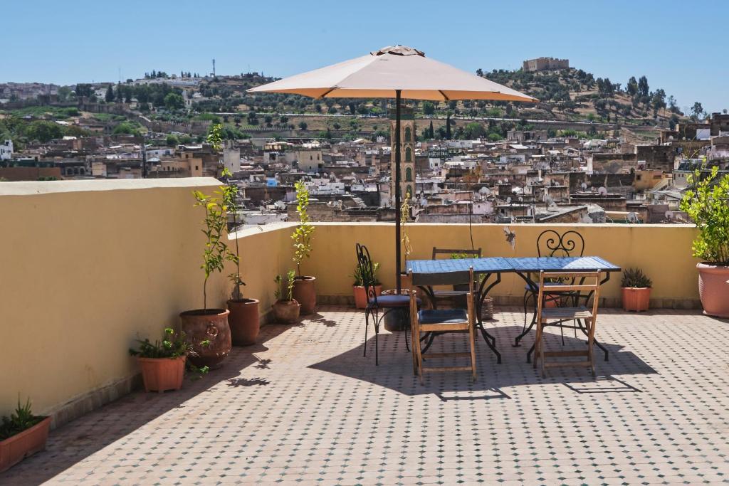 een patio met een tafel en stoelen en een parasol bij Riad Ranya in Fès