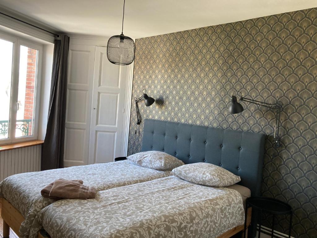 a bedroom with a bed with a blue head board at L'escale Granvillaise in Granville