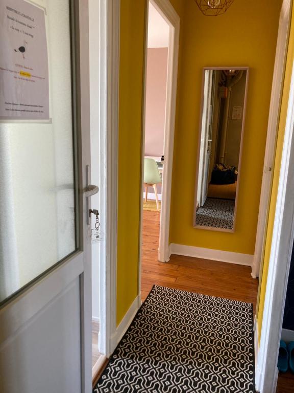 a hallway with yellow walls and a door with a rug at L'escale Granvillaise in Granville