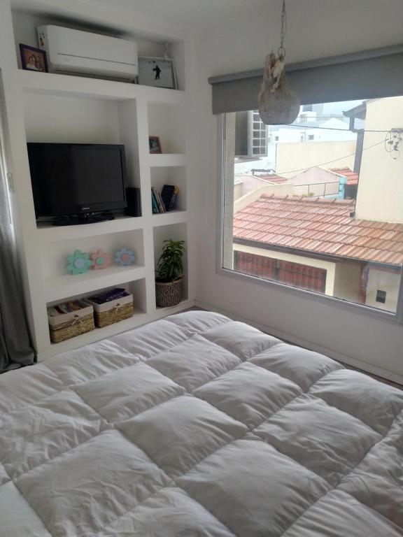 een bed in een kamer met een raam en een televisie bij Departamento en Tandil x 2 in Tandil