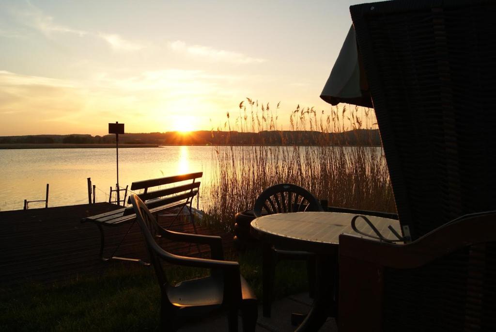 オストゼーバート・ゼリンにある2 Raumwohnung mit sonniger Terrasse und Seeblickのテーブルと椅子が備わる湖上の夕日