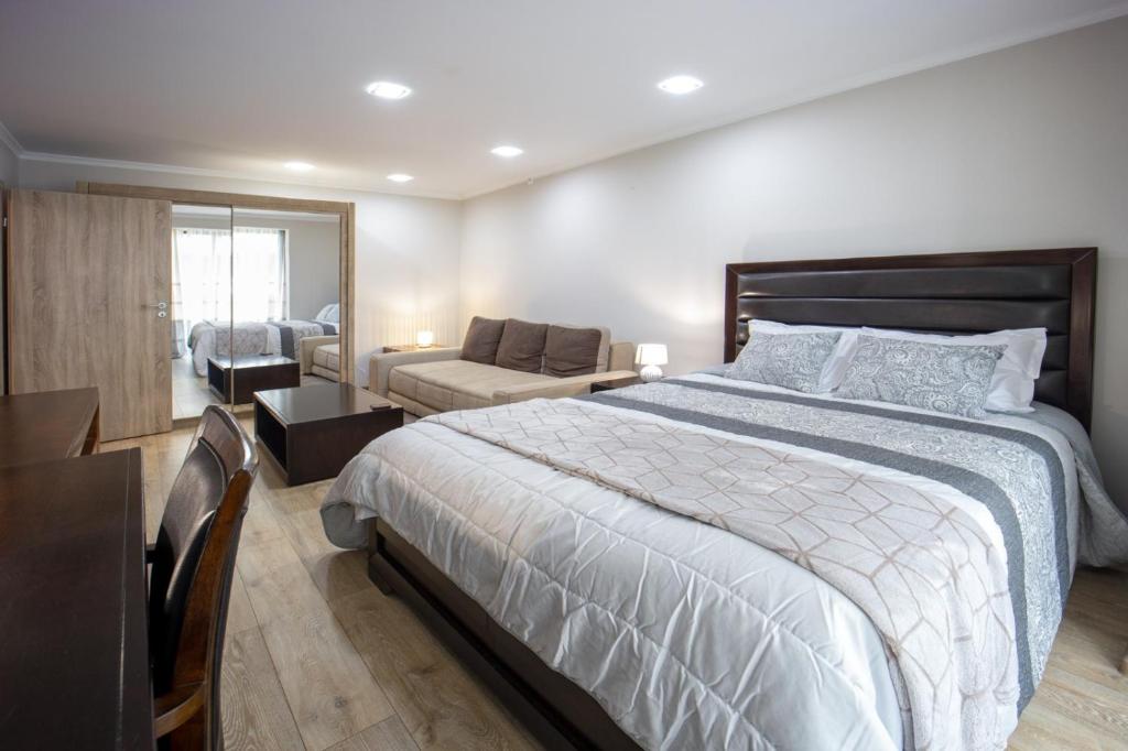 a bedroom with a large bed and a living room at Coresi rezidence & suites in Braşov