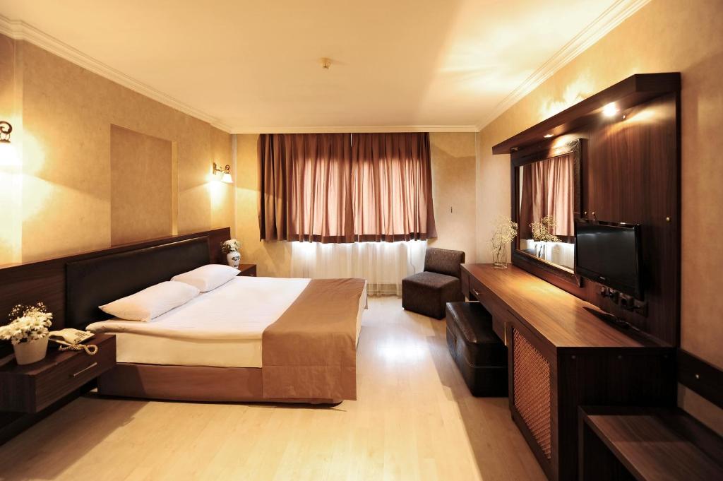 Habitación de hotel con cama y TV en Üstün Hotel Alsancak en İzmir