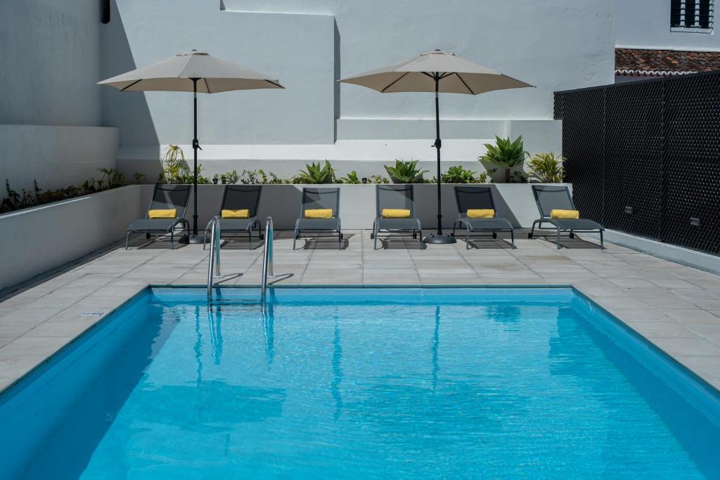 a swimming pool with chairs and umbrellas on a building at Olive Boutique Guesthouse in Vila Franca do Campo