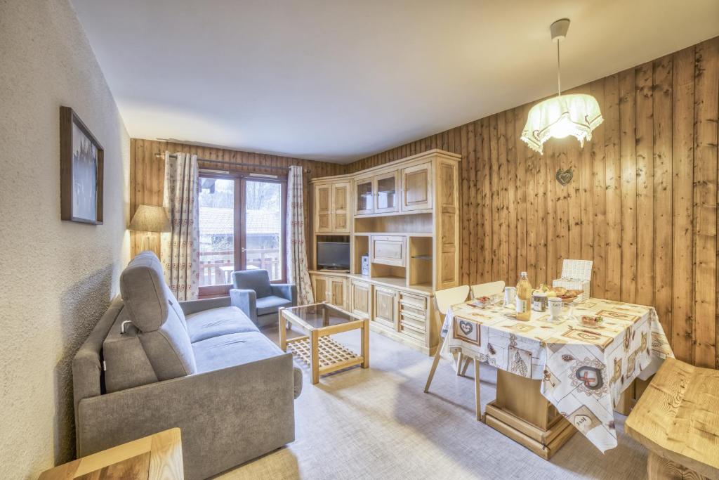 ein Wohnzimmer mit einem Sofa und einem Tisch in der Unterkunft Studio cabine Le Charvet in Le Grand-Bornand