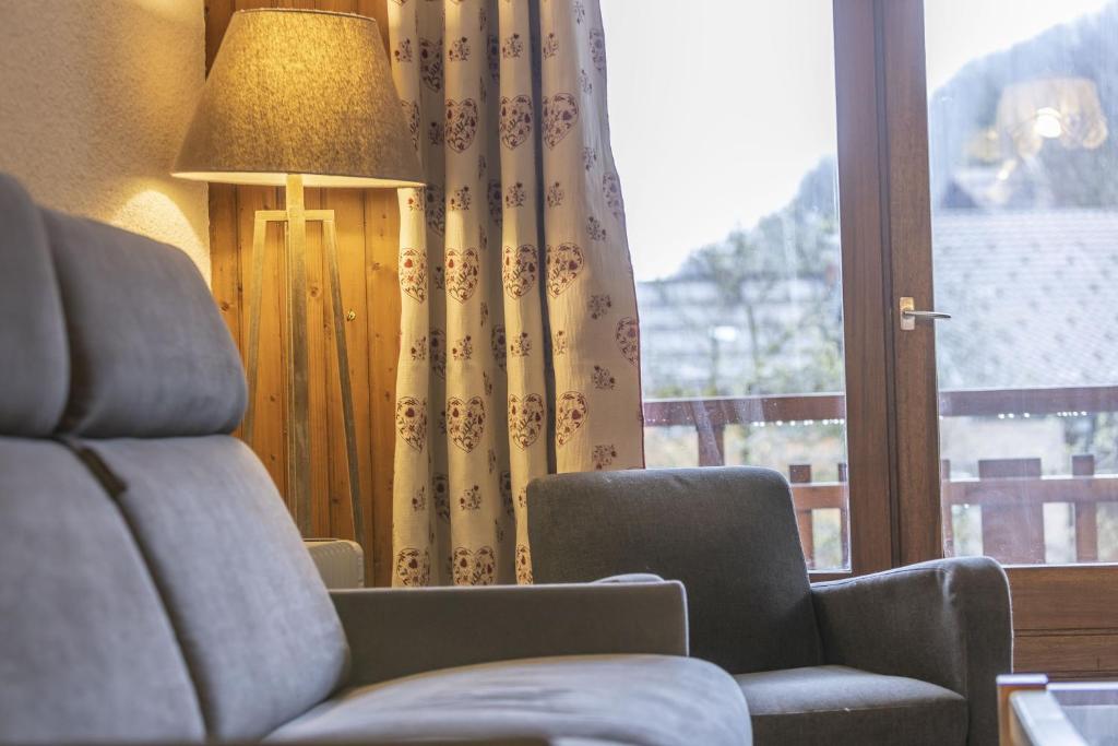 a living room with a chair and a lamp and a window at Studio cabine Le Charvet in Le Grand-Bornand