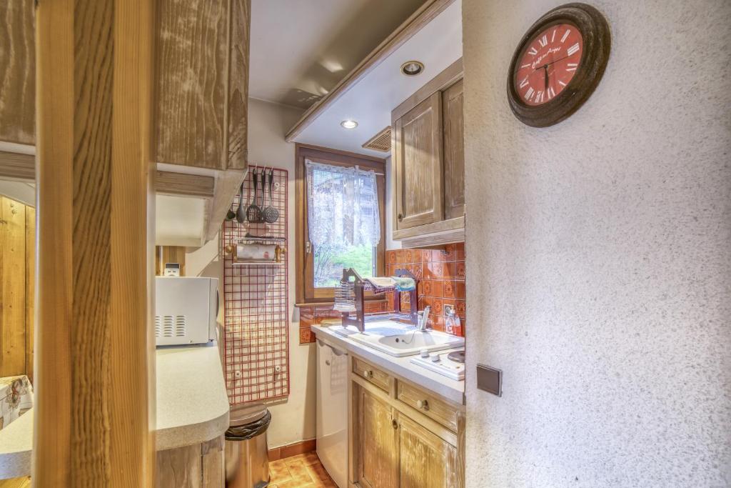 a kitchen with a sink and a clock on the wall at Studio cabine Le Charvet in Le Grand-Bornand