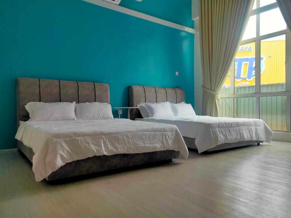 Duas camas num quarto com uma parede azul em SALAM Homestay D'Gerik em Gerik
