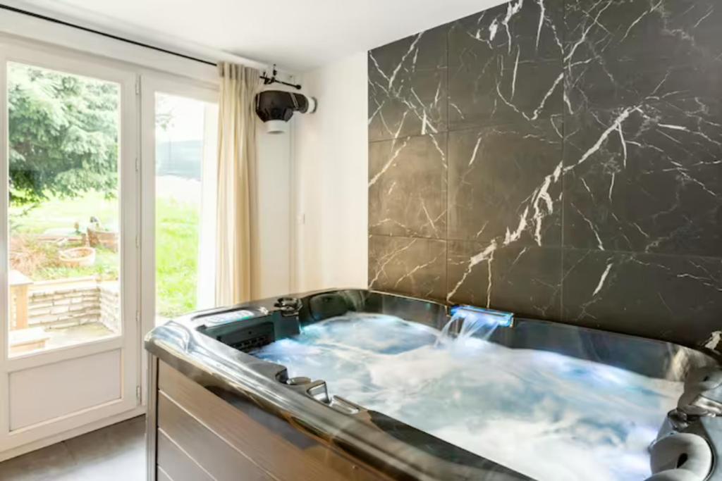 une baignoire jacuzzi dans une cuisine avec un mur en marbre dans l'établissement LE CHILL Suite & SPA (Jacuzzi et Sauna privés), à Boissy-Saint-Léger