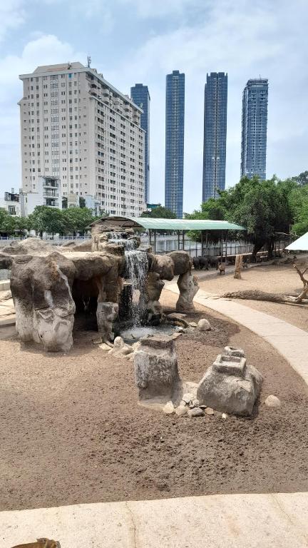 a stone fountain in a park with tall buildings at Nhà nghỉ trà my 
