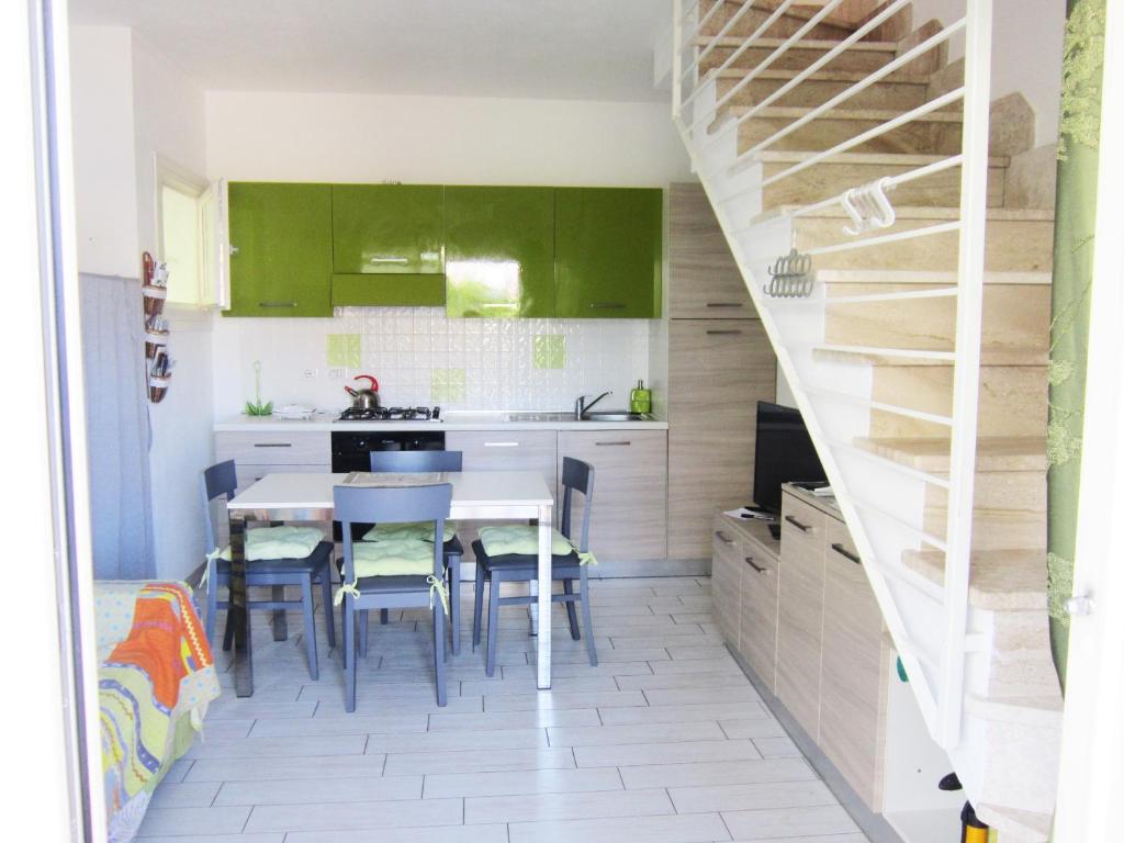 Lu RazzoniにあるAffittimoderni Viddalba Termeのキッチン(緑のキャビネット、テーブル、椅子付)