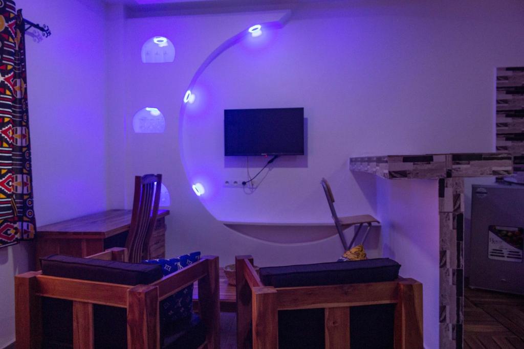 Zimmer mit einem lila Zimmer mit Stühlen und einem TV in der Unterkunft les perles du bonheur Nyékonakpoé in Lomé