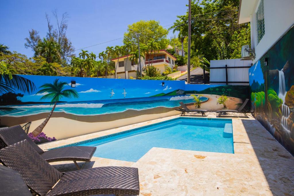 a swimming pool with two chairs and a fence at Chris Guest House in Rincon