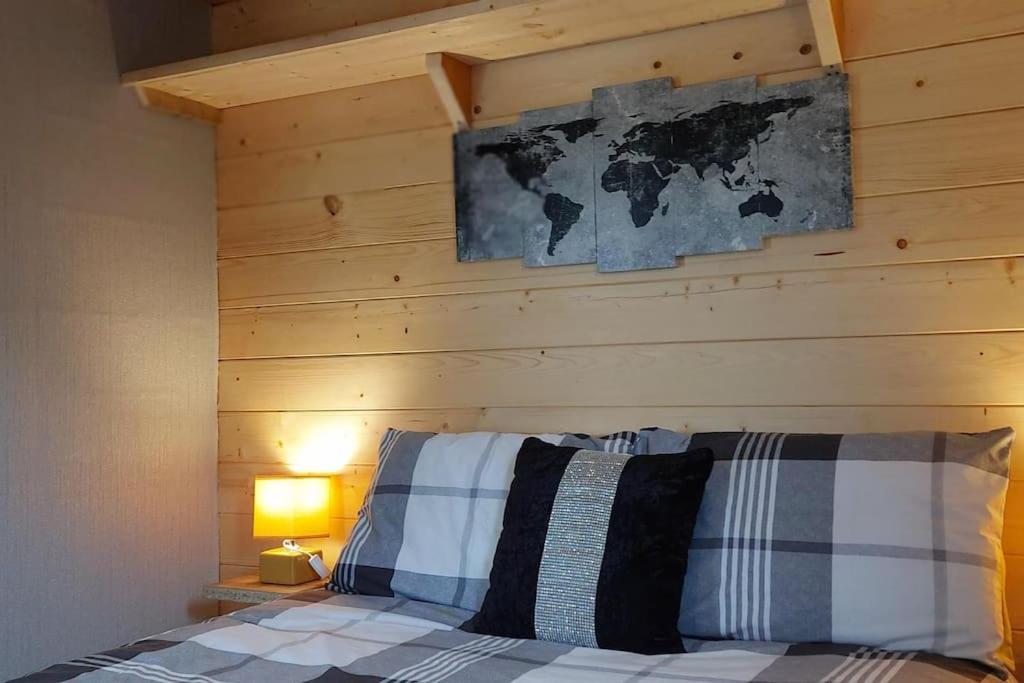 a bed with a wooden wall with a map above it at The Stunning Log House in Wexford