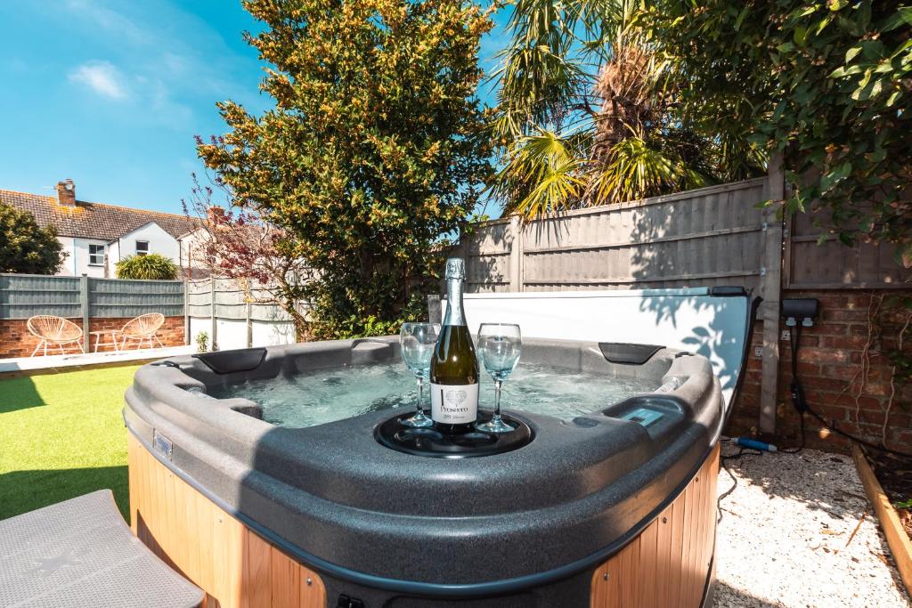 a hot tub with a bottle of wine and a glass at Opulent Dorset Gem with Hot-Tub - Parking - Pets in Weymouth