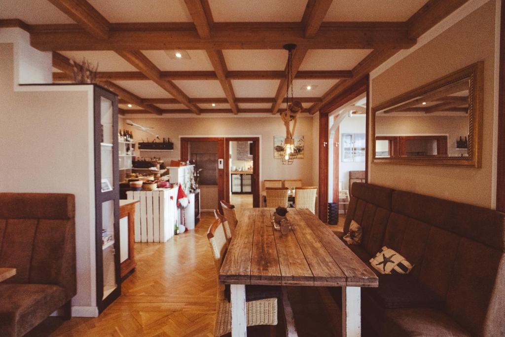 a living room with a wooden table and a kitchen at Hotel Villa Schwanebeck in Binz