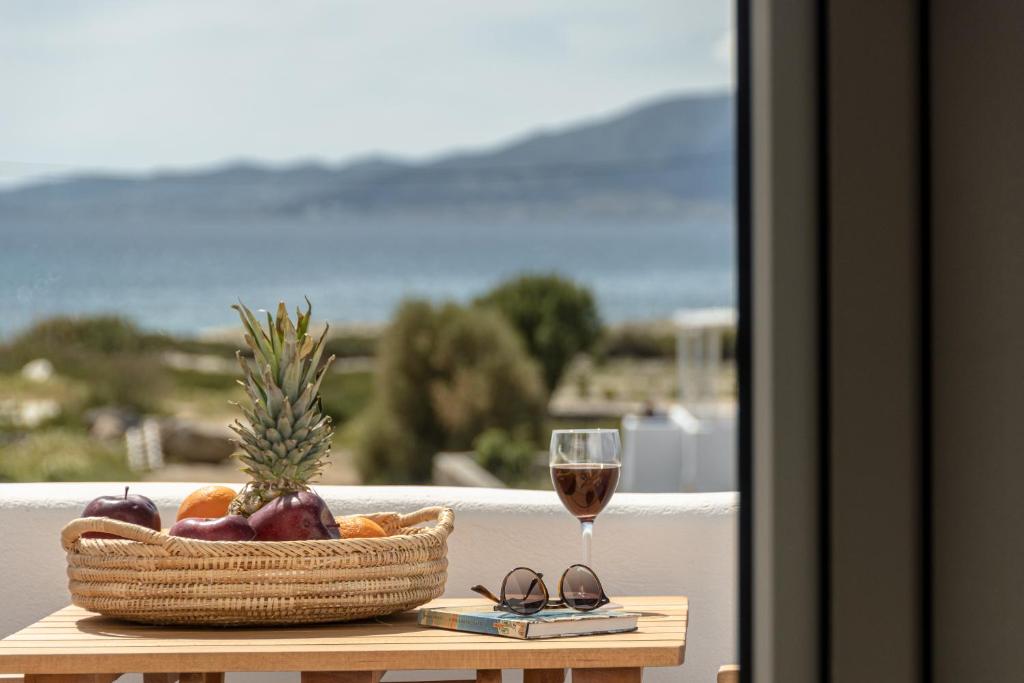kosz owoców i kieliszek wina na stole w obiekcie Sunshine Plaka Naxos w mieście Plaka