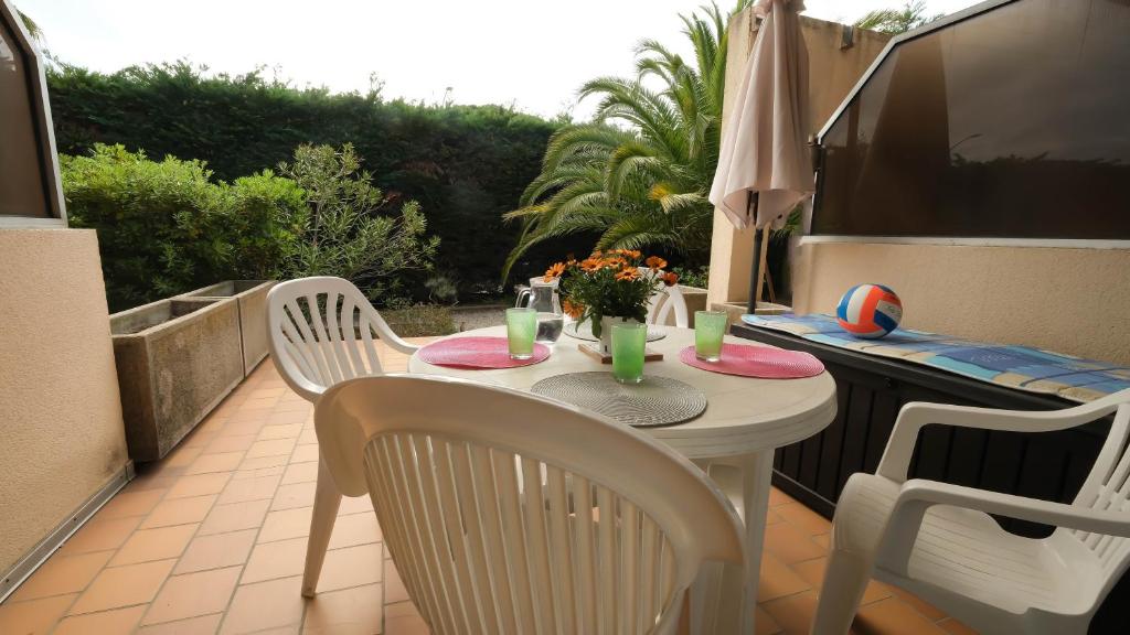 - une table et des chaises sur une terrasse avec un parasol dans l'établissement Rez de jardin à 100m de la mer, à Cavalaire-sur-Mer
