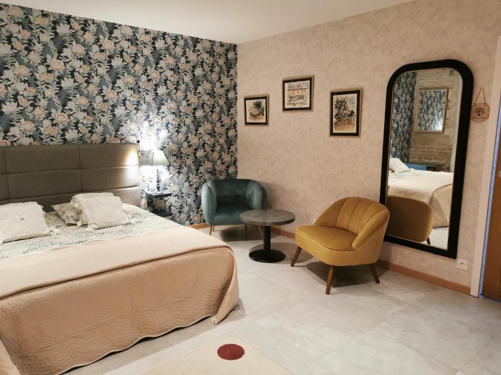 una camera con letto, specchio e sedia di Chambre de l'Iris a Sainte-Croix-sur-Mer