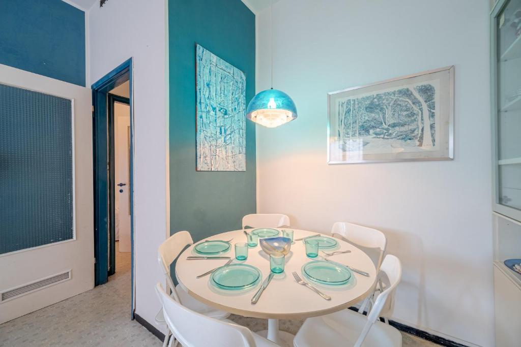 uma sala de jantar com uma mesa e cadeiras brancas em INTO THE BLUE Lavagna Seaside Flat em Lavagna