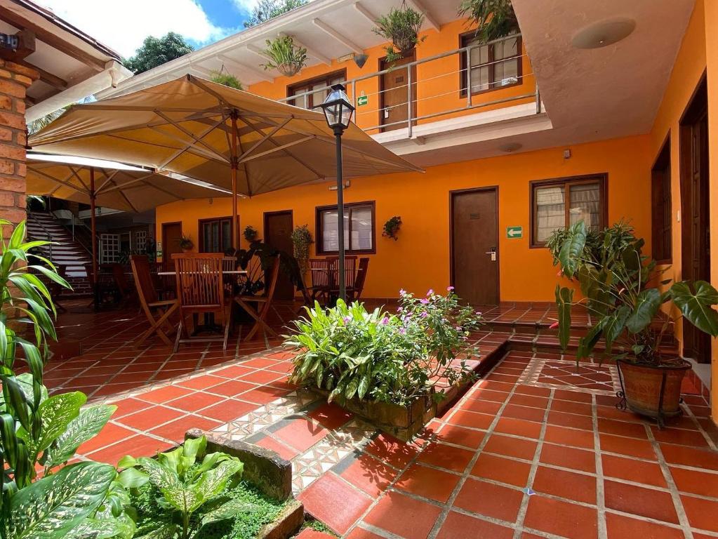 ein orangefarbenes Haus mit einer Terrasse mit einem Tisch und einem Sonnenschirm in der Unterkunft Posada El Remanso de Pueblo Nuevo in San Cristóbal