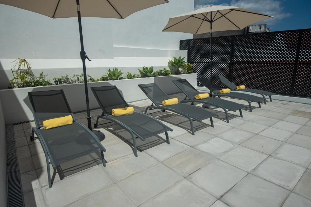 a row of chairs with umbrellas on a patio at Olive Boutique Guesthouse in Vila Franca do Campo