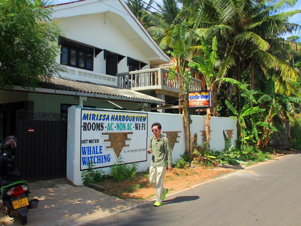 a man walking down a street in front of a house at Mirissa Harbour View in Mirissa