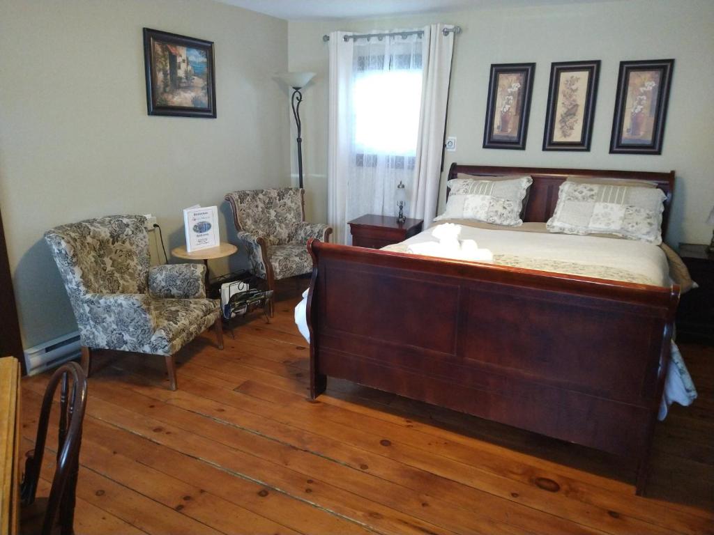 ein Schlafzimmer mit einem Bett und einem Stuhl in der Unterkunft Au Coeur De Magog in Magog-Orford