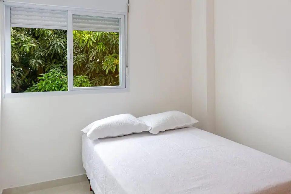 een witte kamer met een bed en een raam bij Apê 2 in Sao Paulo