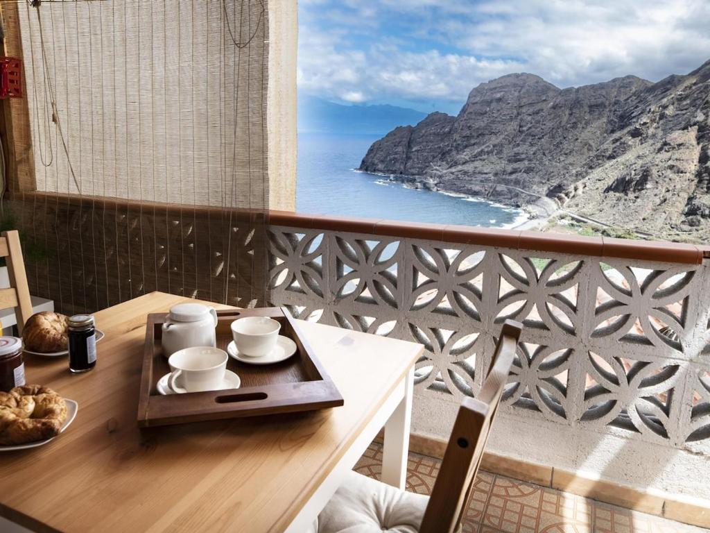 a balcony with a table with a view of the ocean at Lightbooking Patio tipico canario Hermigua in Hermigua