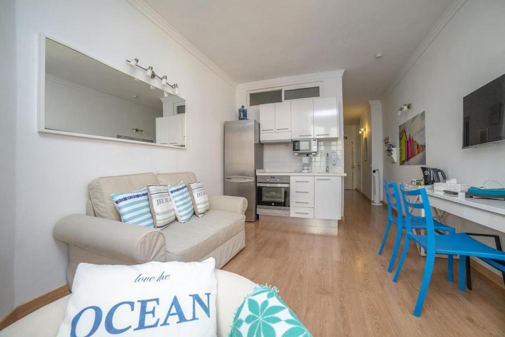 a living room with a couch and a table and a kitchen at Lightbooking Canteras Beach in Las Palmas de Gran Canaria