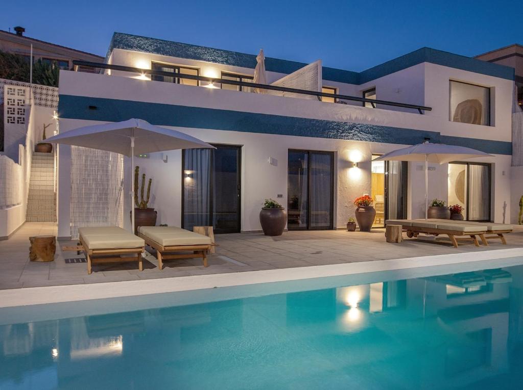 una villa con piscina di fronte a una casa di Lightbooking Edem Playa del Hombre a Telde