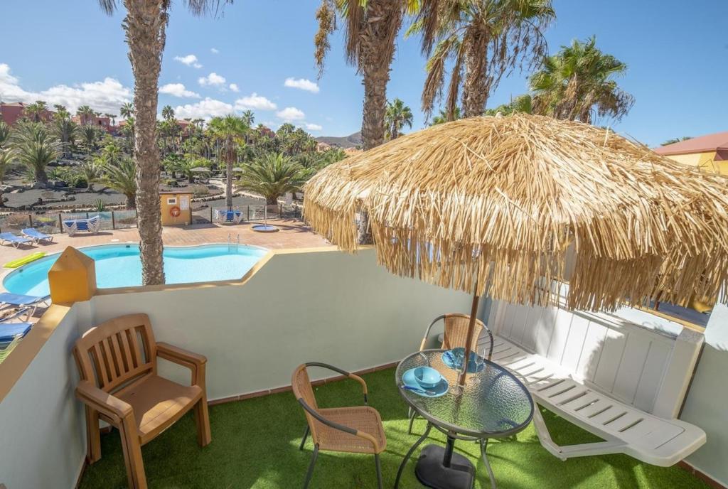 コラレホにあるLightbooking Oasis Royal Corralejoのパティオ(テーブル、椅子付)、プールが備わります。