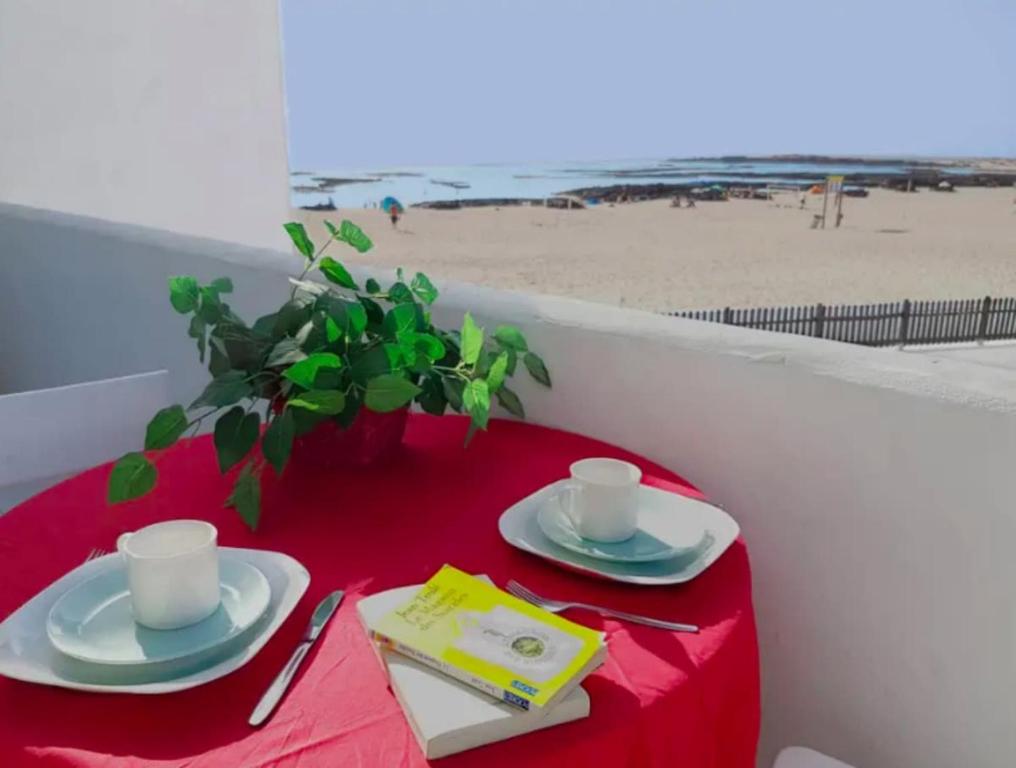 a table with a red table cloth and two cups and plates at Lightbooking Los Lagos El Cotillo in Cotillo