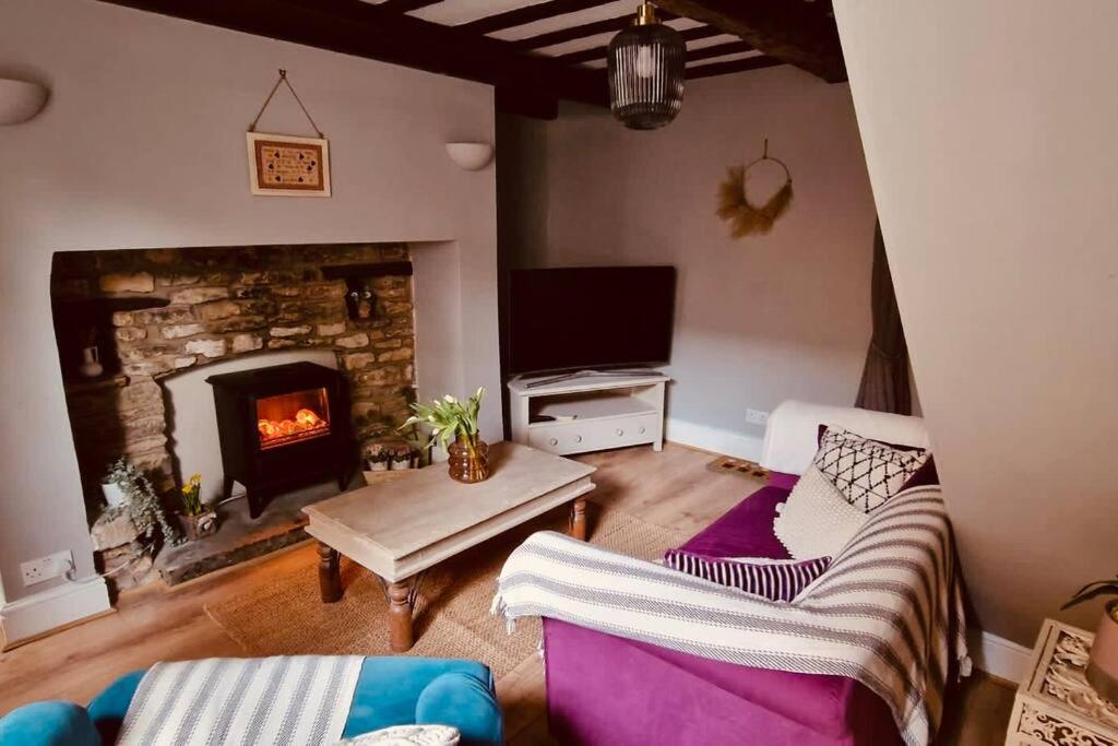 a living room with a couch and a fireplace at Hideaway Cottage Sleaford in Sleaford