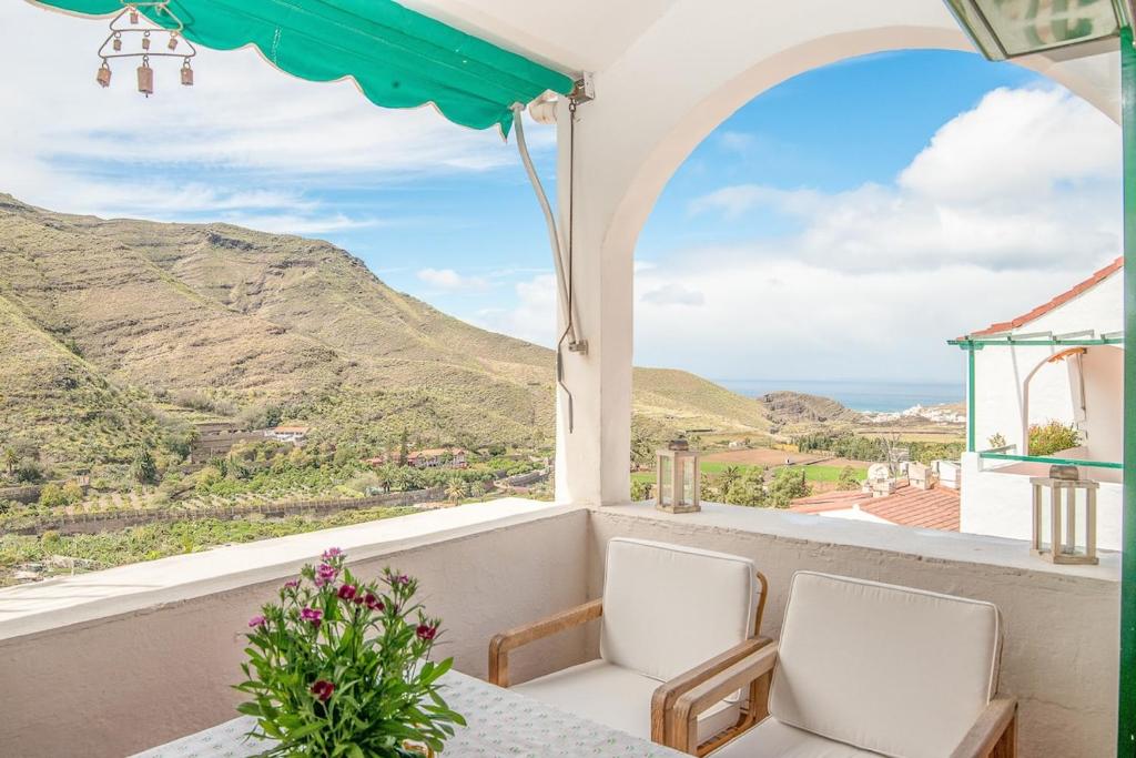 balcone con tavolo, sedie e vista sulle montagne. di Casa Carmen Agaete Vista al Mar ad Agaete