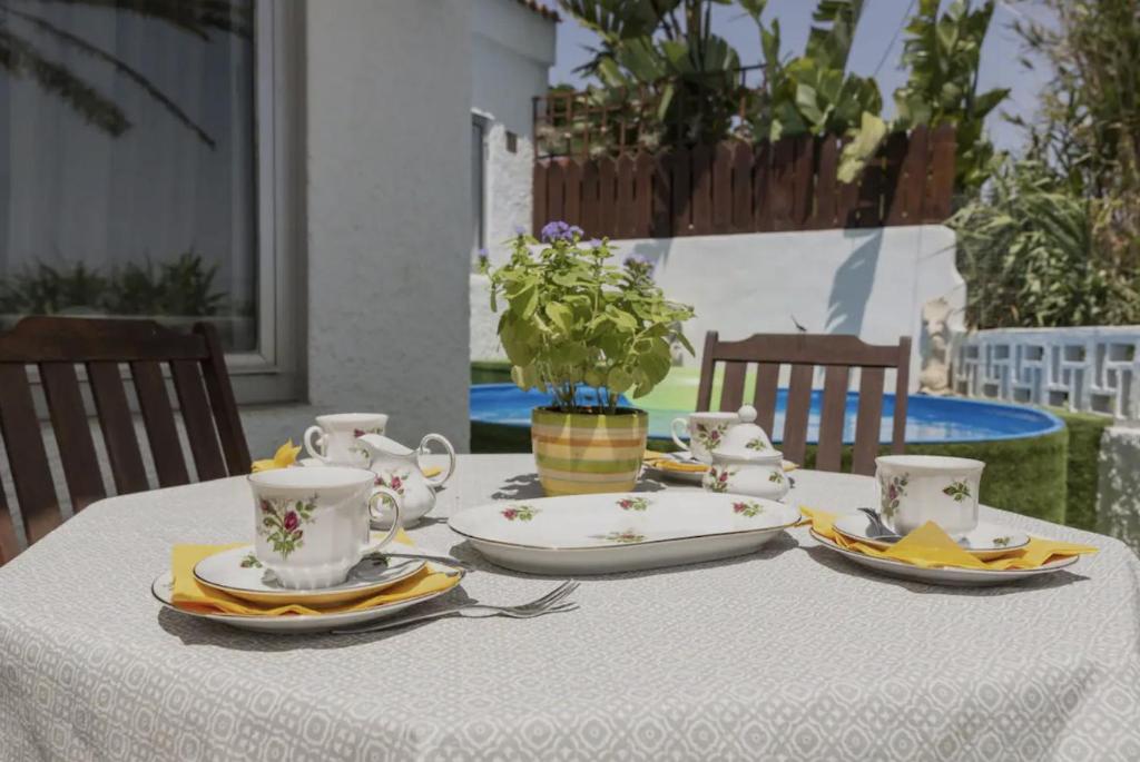 una mesa con platos y tazas y un jarrón con flores en Lightbooking Telde Lomo Salas Dey, en Telde