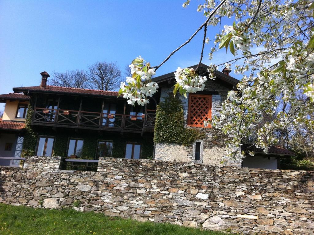 ein Haus mit einer Steinmauer und blühenden Bäumen in der Unterkunft Il Ciliegio Selvatico in Verbania