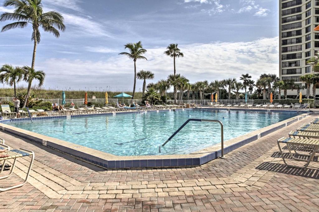 a large swimming pool with chairs and palm trees at Sunny Ocean Village Condo with Community Pool! in Fort Pierce
