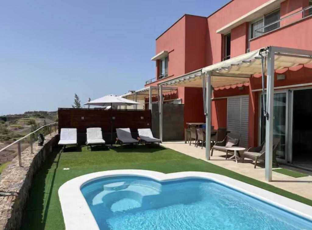un patio trasero con piscina y una casa en Lightbooking piscina privada Salobre Golf, en San Bartolomé