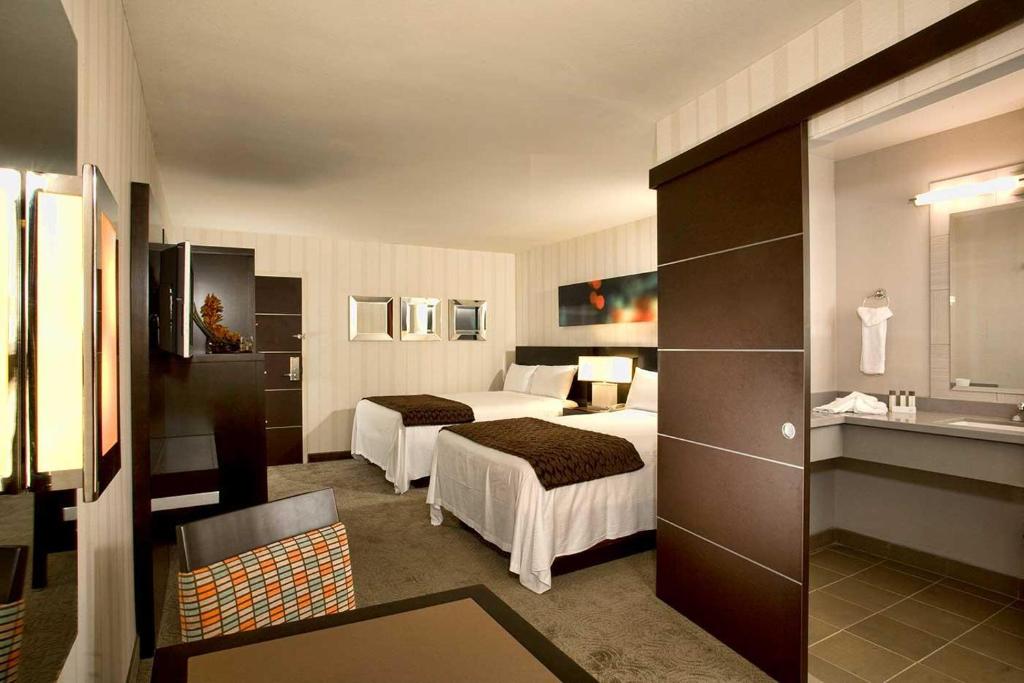 a hotel room with two beds and a bathroom at Gold Coast Casino by the Strip Las Vegas in Las Vegas