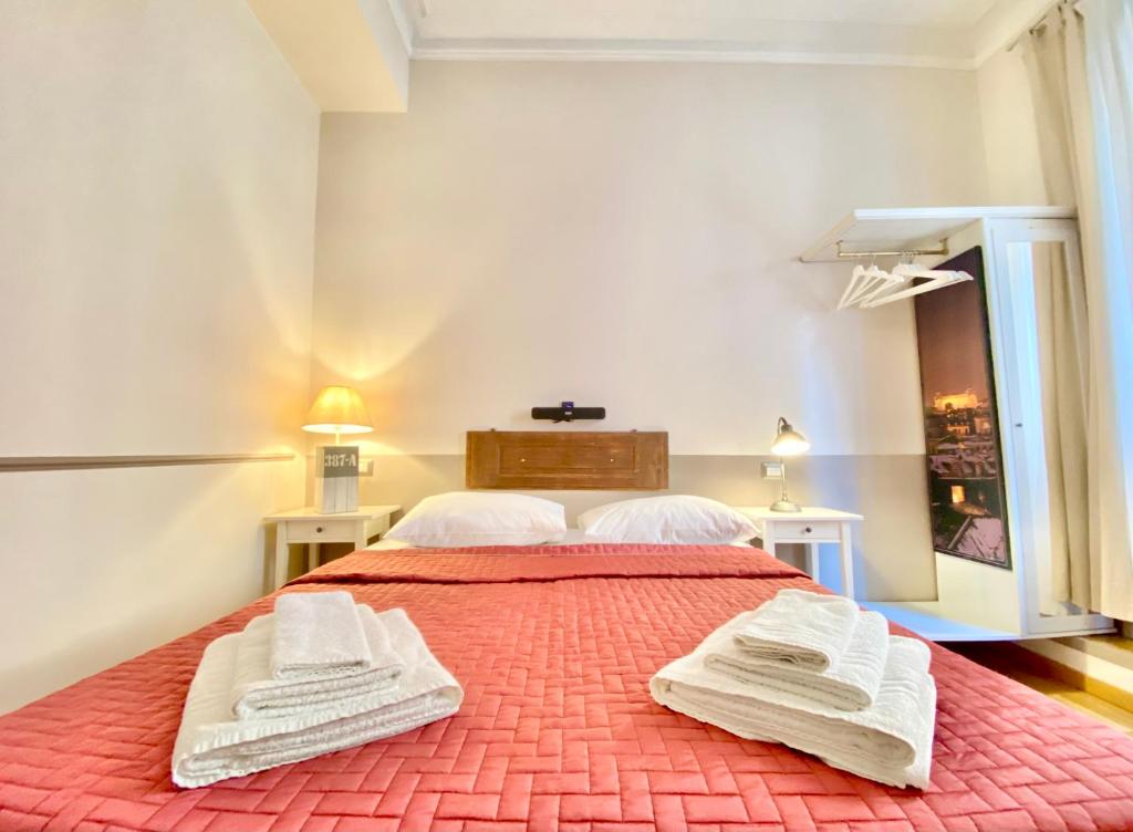 sypialnia z czerwonym łóżkiem i 2 białymi ręcznikami w obiekcie Roome B&B w Rzymie
