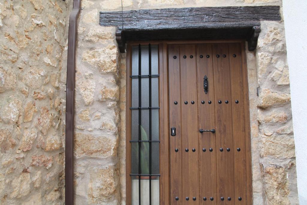 uma porta de madeira num edifício de pedra com uma janela em EL CORRAL DE LA VERA em Losar de la Vera