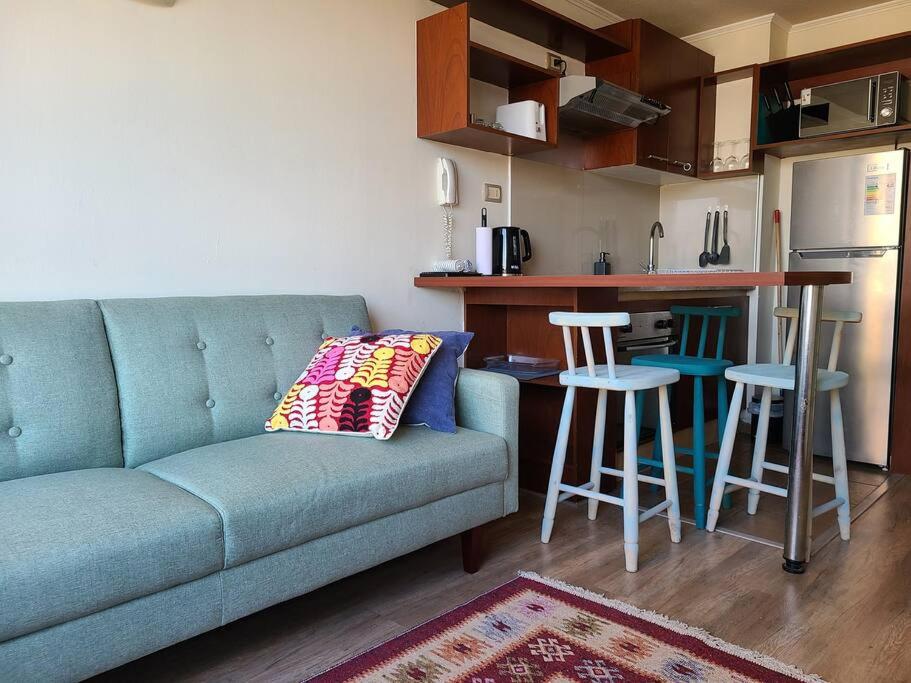 sala de estar con sofá azul y cocina en Departamento Santa Lucía, en Santiago