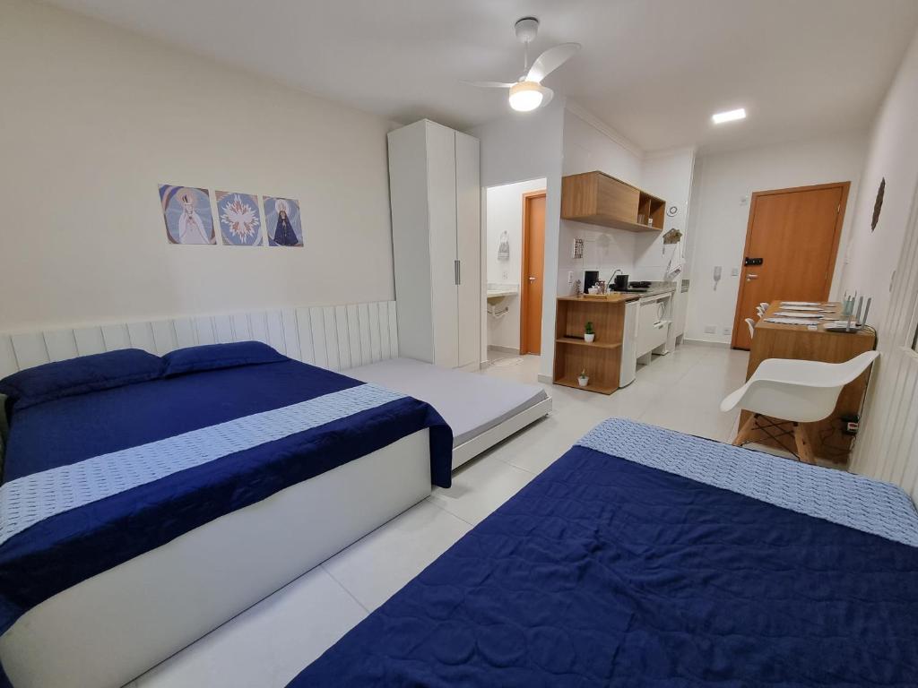 um quarto branco com 2 camas e uma cozinha em Morada da Fé II à 300 m da canção nova Cond. da Fé em Cachoeira Paulista
