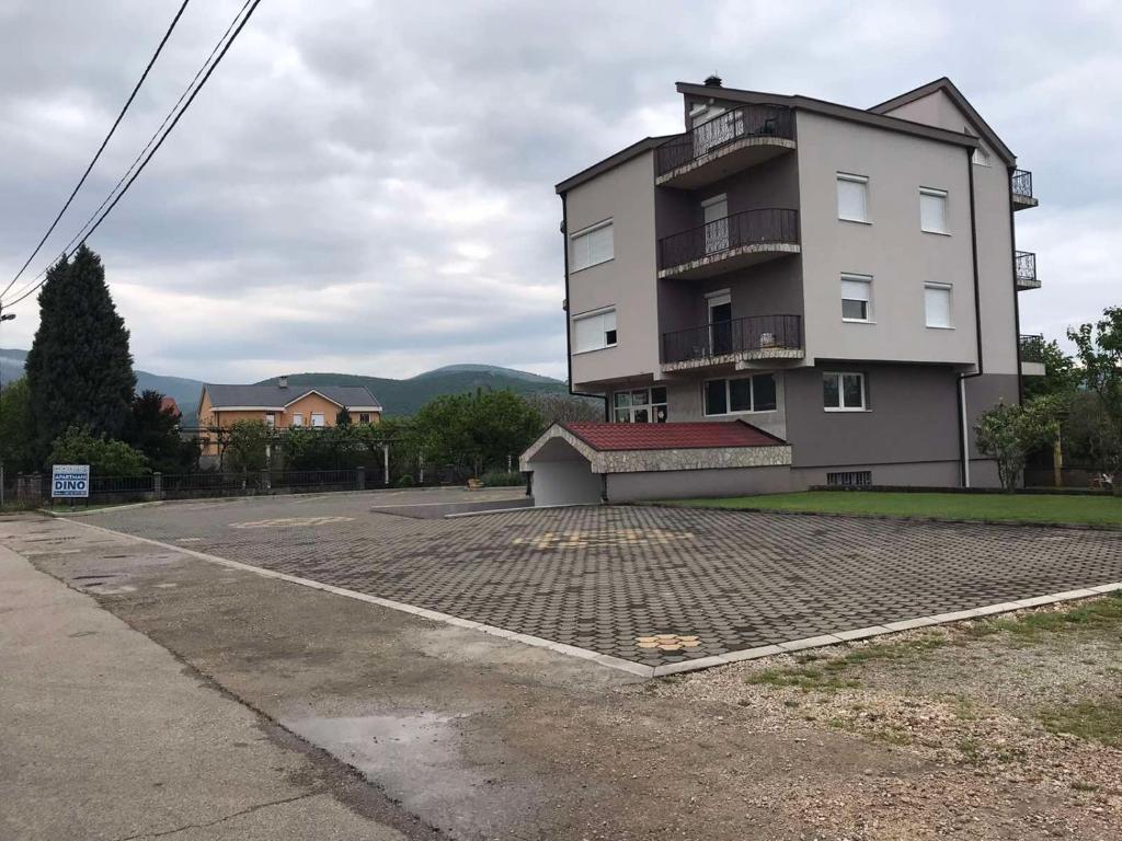 un gran edificio con un estacionamiento delante de él en Apartmani Dino Blagaj, en Blagaj