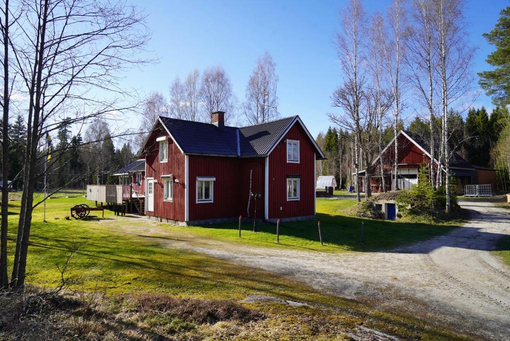 ein rotes Haus mit schwarzem Dach neben einer Straße in der Unterkunft Holiday Home Bengtsfors in Bengtsfors