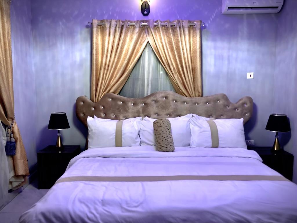 1 dormitorio con 1 cama grande y paredes moradas en The Moonshine Residence-Royal, en Nnewi
