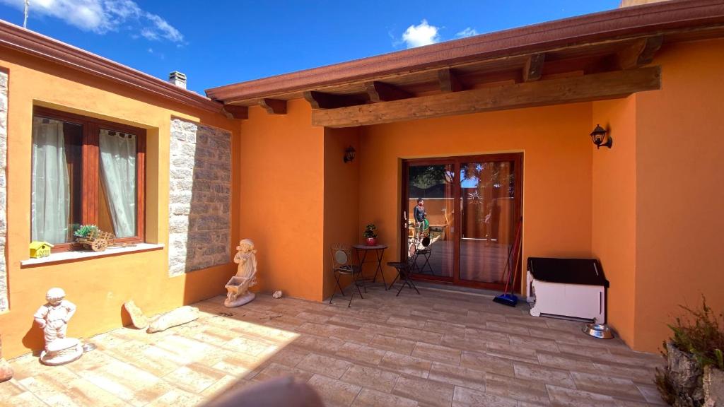 an orange house with a patio with a piano at Fadda Holiday House - Managed By Antonio Sanna in Austis