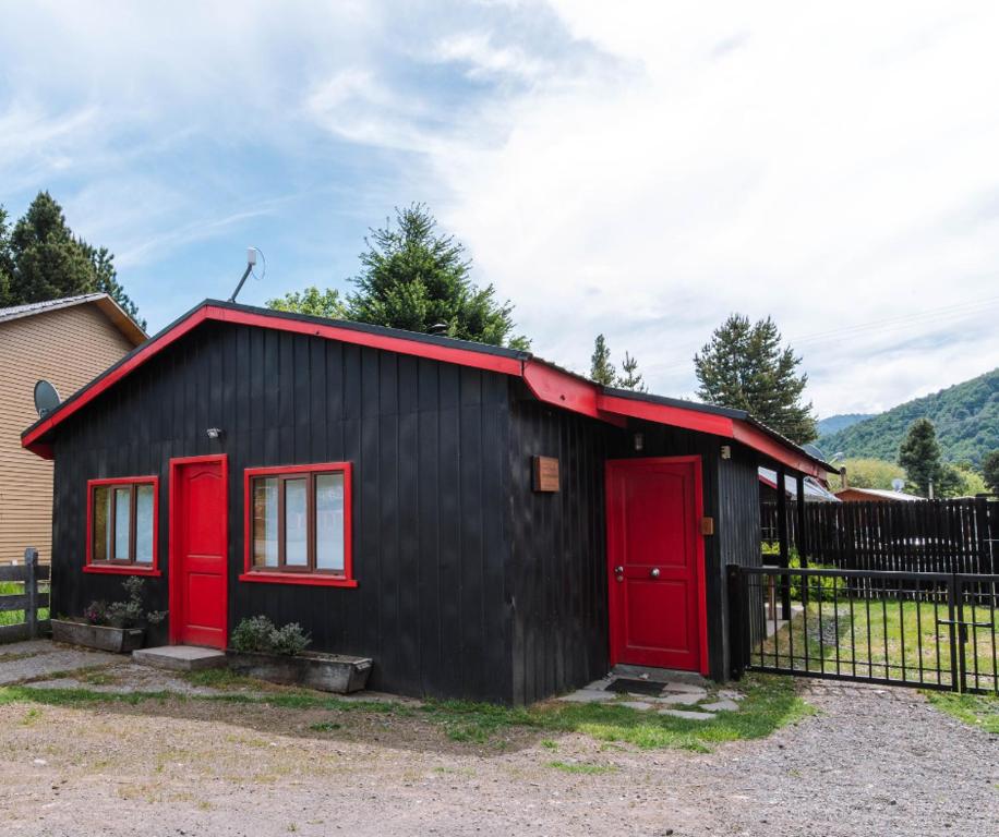 a black and red house with red doors at Refugio Simple Sur Casa 4 - 5 personas in Malalcahuello